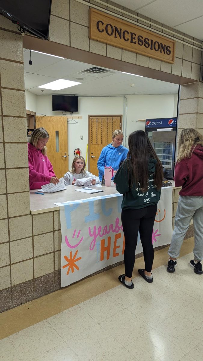 Kendra Knutson (12), Sydney Kokot (12), and Kallie Studier (11), distribute the 2024 Golden Year Yearbook during lunches on May 9th and 10th. 